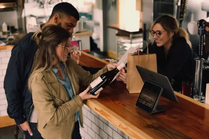 woman holding wine bottle beside man in front of woman smiling